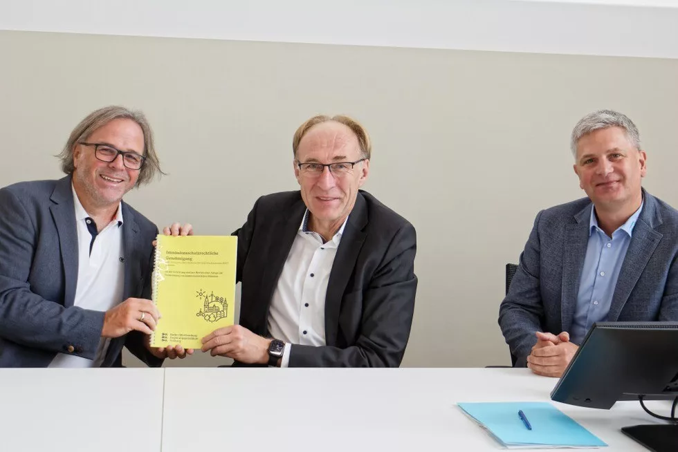 Feierliche übergabe: Regierungspräsident Carsten Gabbert (l.) überreicht dem Verbandsvorsitzenden Martin Haag die unterzeichnete immissionschutzrechtliche Genehmigung für den Bau und Betrieb der Verbrennungsanlage für Klärschlamm. Rechts KZV-Geschäftsführer Mirco Ebeling. Foto: Ruth Seitz